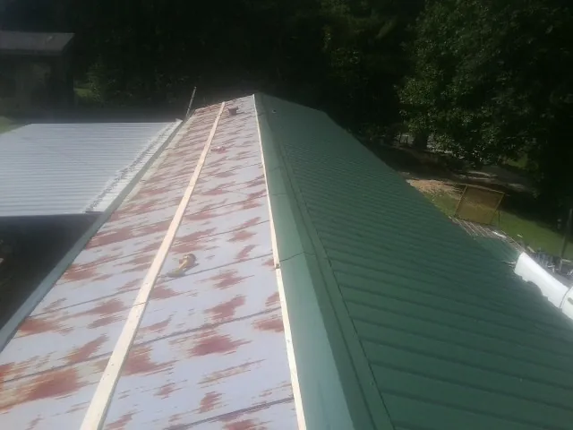Old rusted panels beside newly installed green metal roofing — Wind Damage Roof Repair by Roofing Brothers in Jenkinsville