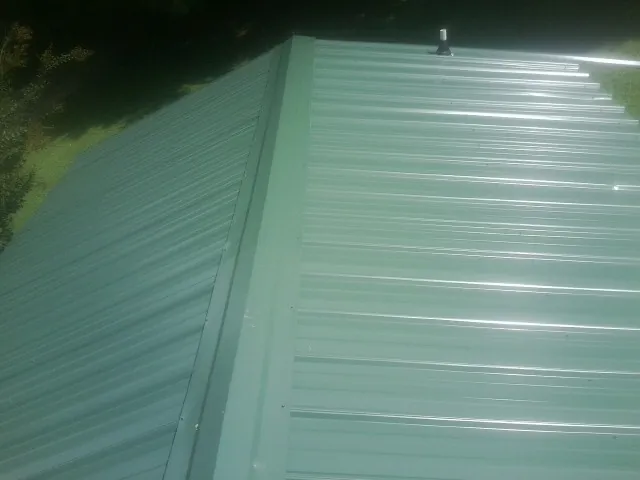 New green metal panels meeting at the ridge of a roof — Flat Roof Repair work by our crew in Jenkinsville