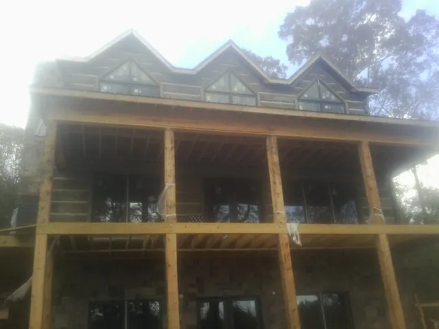 Dormers and porch framing on a large log home under construction — Roof Coating work by our crew in Jenkinsville
