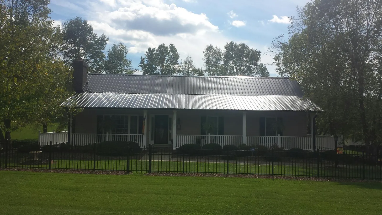 Gray metal roof on a brick ranch with a full width front porch — Gutter Guard Installation work by our crew in Jenkinsville