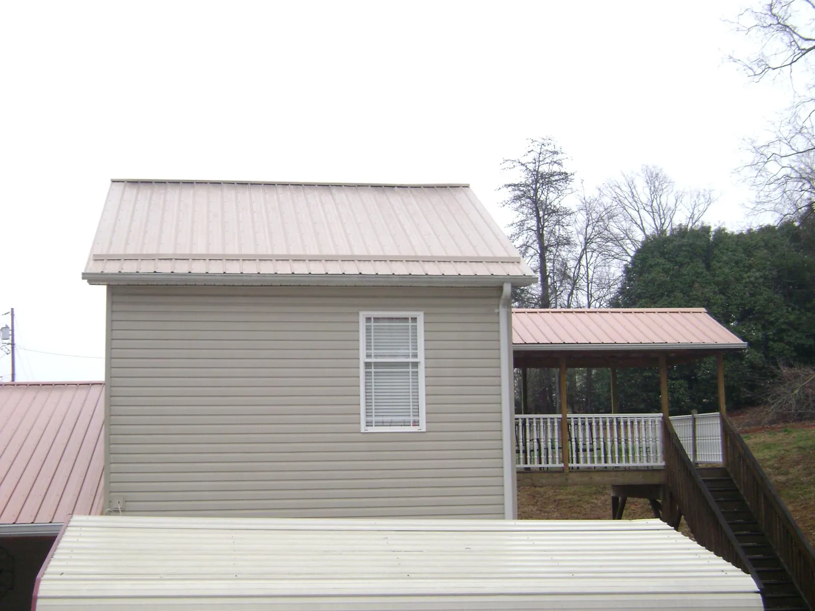 Tan metal roofs on a two story addition and attached porch, from a Roof Replacement job in Jenkinsville