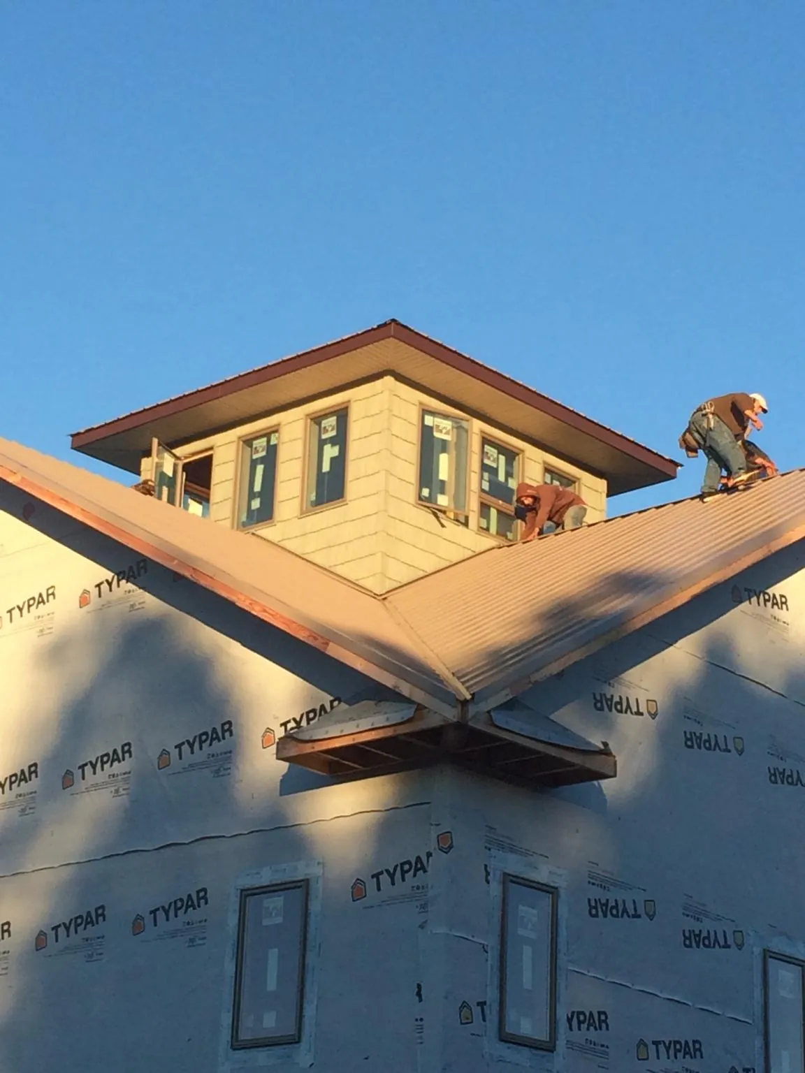 Roofers working around a rooftop cupola on a new metal roof at sunset — Roof Waterproofing in Jenkinsville by Roofing Brothers